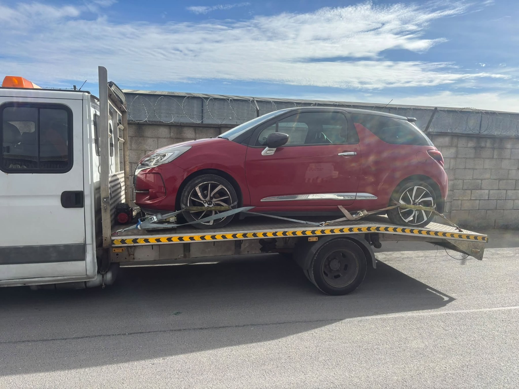 Red car transported on recovery truck